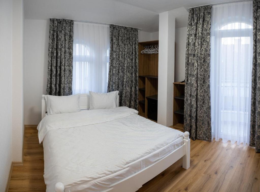 a white bed in a room with windows at Hotel Lux in Struga