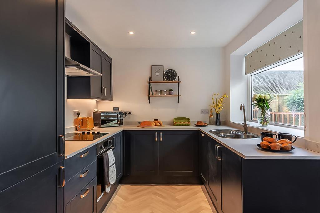 a kitchen with black cabinets and a sink and a window at The Harrogate House - 4 Bed Townhouse in Harrogate