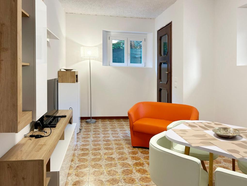 een woonkamer met een tafel en een oranje stoel bij Il Nido di Moggio - Nibbio Apartment in Moggio