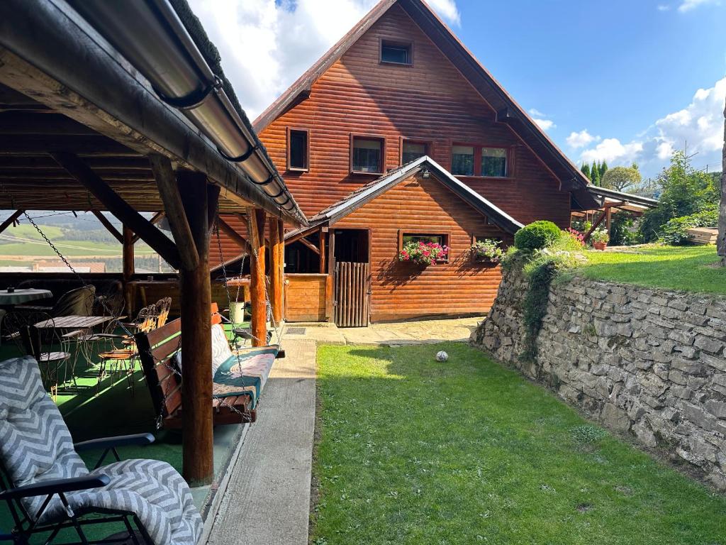 a wooden house with a stone wall in front of it at Ubytovanie Privat Antoni - apartmán v RD in Lazy pod Makytou