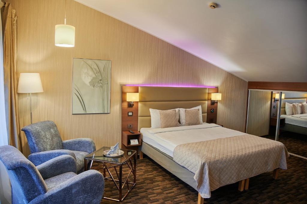 een hotelkamer met een bed en twee stoelen bij Olympus Hotel in Kaunas