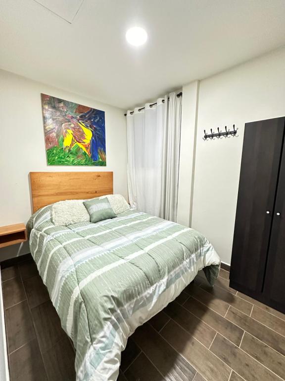 een slaapkamer met een bed en een schilderij aan de muur bij Departamento Roma 1 CDMX in Mexico-Stad