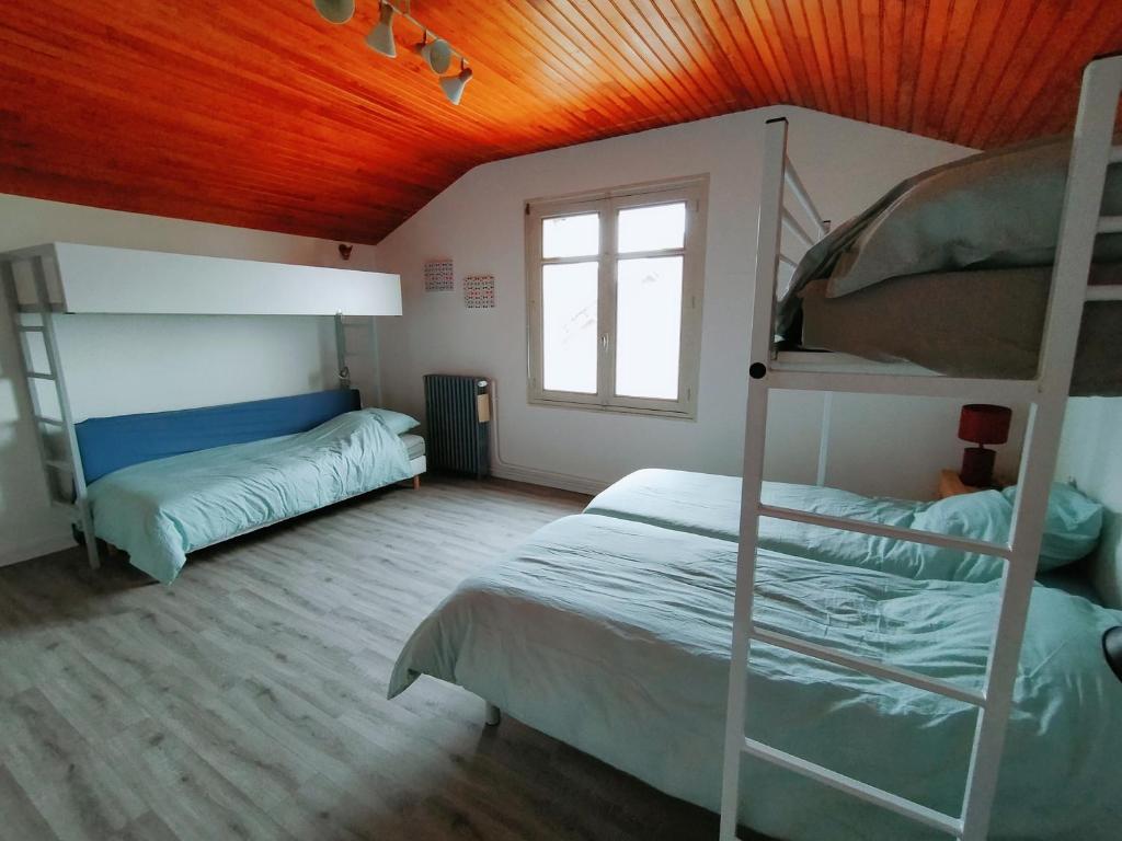 a bedroom with two bunk beds and a wooden ceiling at La Pause Vélo gite d'étape in Guéret