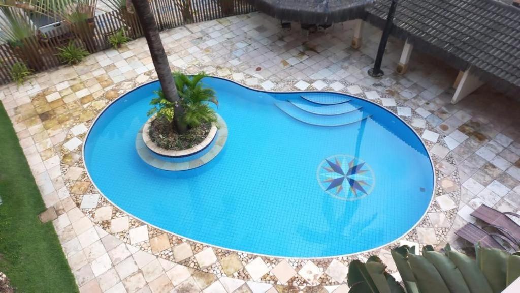 an overhead view of a blue pool with a palm tree and an umbrella at Cumbuco Residence - Beach in Cumbuco