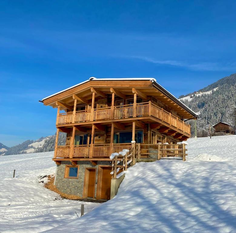 una cabaña de madera en la nieve con nieve en Chalet - Das Schrofen, en Ramsau im Zillertal
