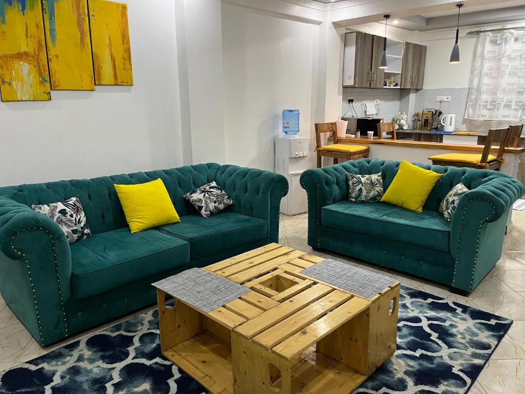 uma sala de estar com dois sofás verdes e uma mesa de centro em The pine 2 bedroom house California plaza em Nanyuki