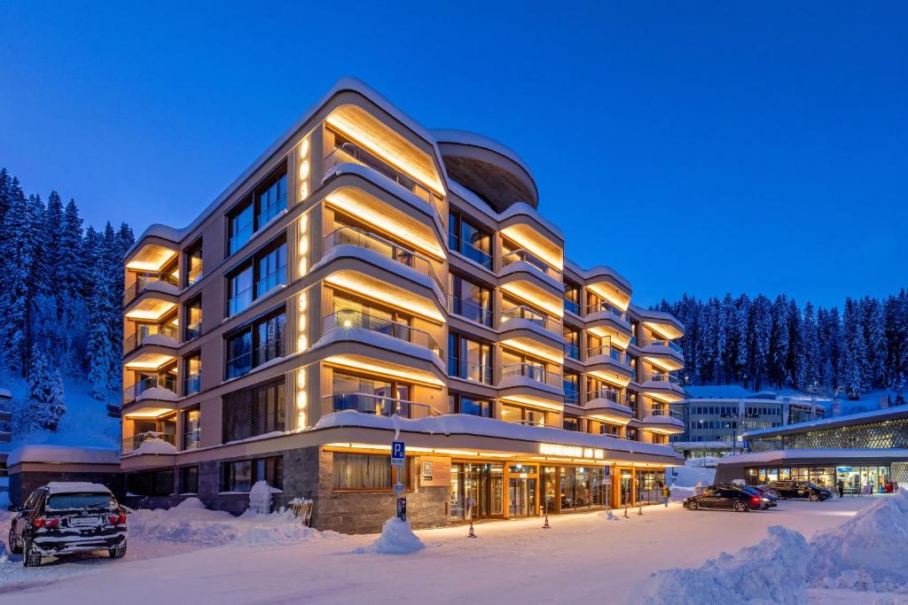 un grande edificio nella neve di notte di Postresidenz am See a Arosa