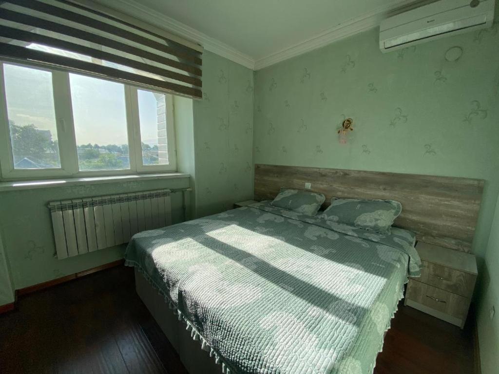 ein Schlafzimmer mit einem Bett und zwei Fenstern in der Unterkunft Pamir Hotel-Hostel in Duschanbe