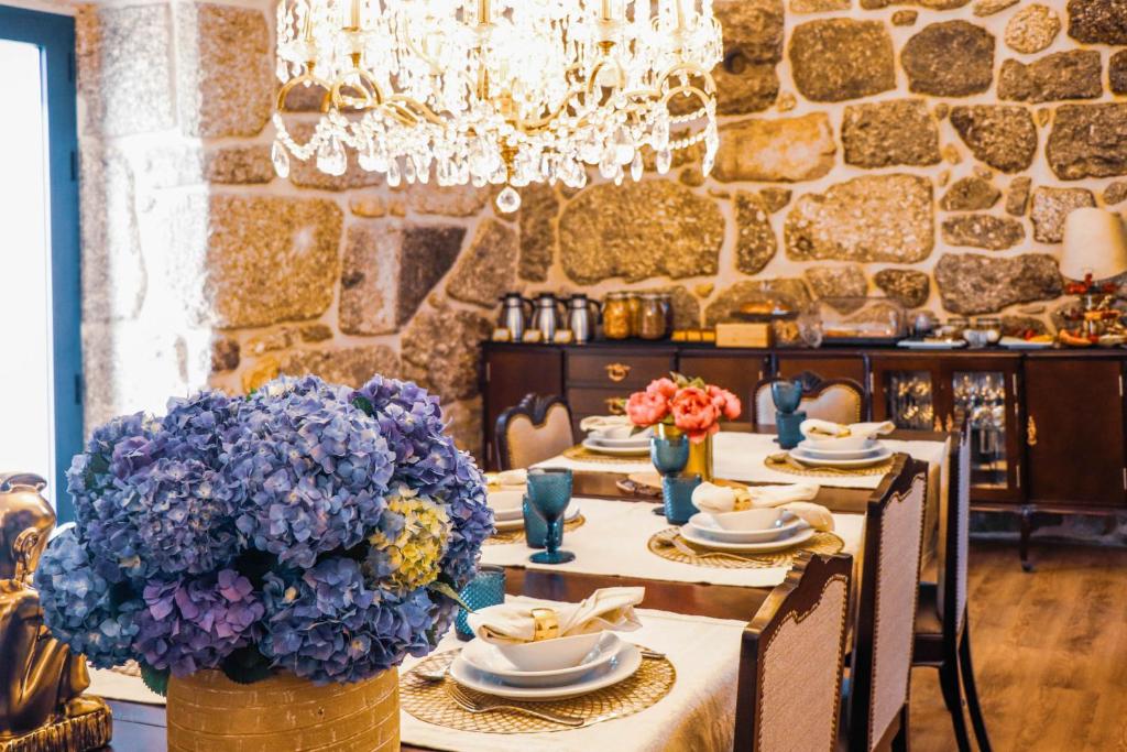 un comedor con una mesa con platos y flores en Vale da Fonte - Charming Houses, en Ponte da Barca