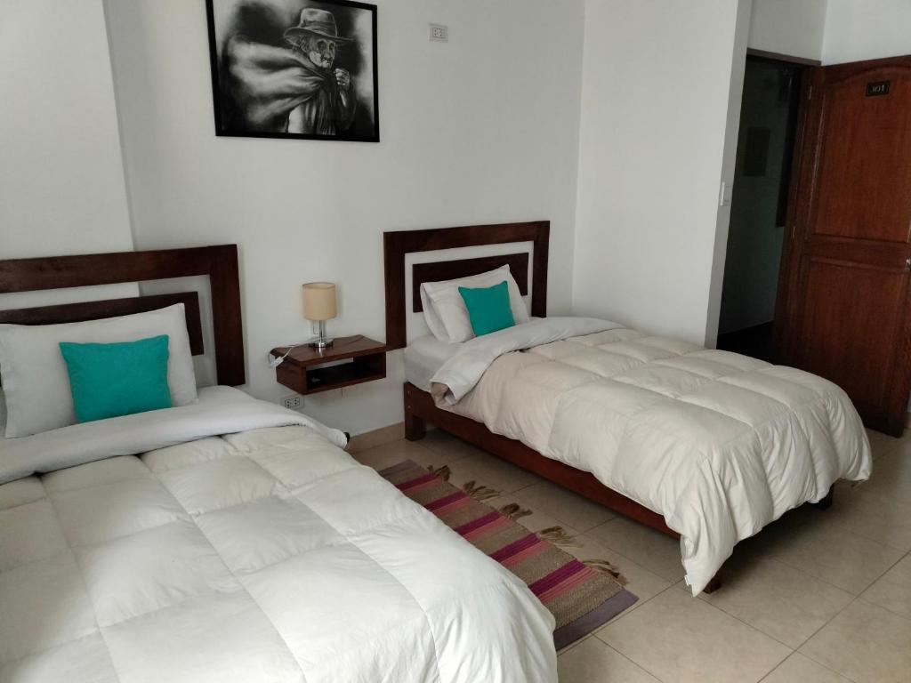 2 camas en una habitación con almohadas blancas y azules en Samuel's House, en Machu Picchu