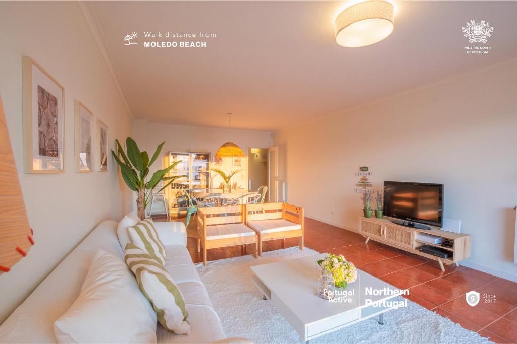 sala de estar con sofá blanco y TV en Portugal Active Moledo Beach House, en Moledo