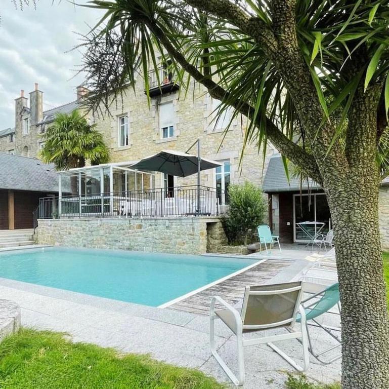 a swimming pool with two chairs and a house at Villa Tourelle in Dinan