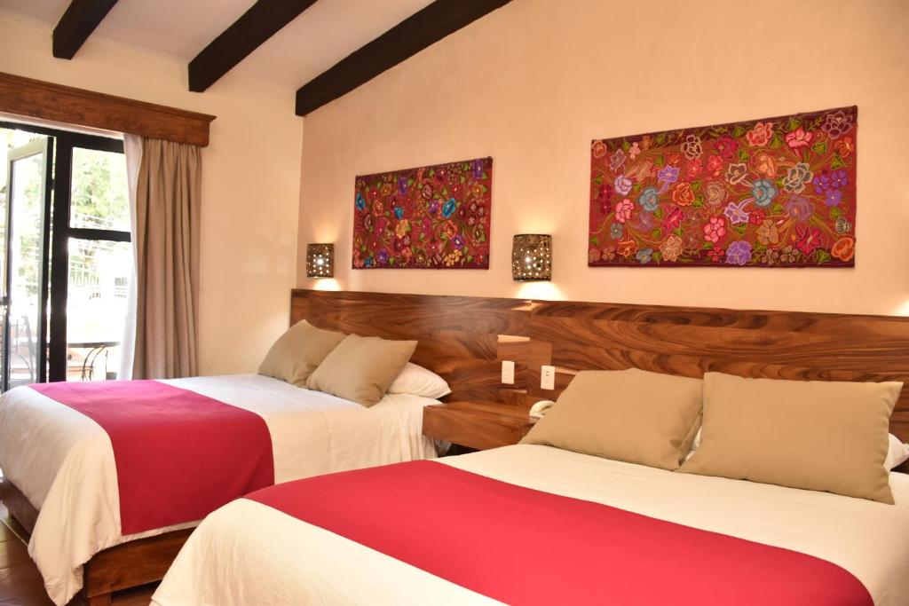 una camera d'albergo con due letti rossi e bianchi di Hotel Mansion Del Valle a San Cristóbal de Las Casas