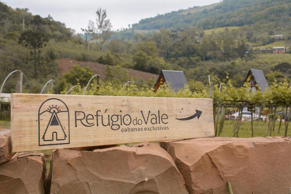 a wooden sign on a wall in front of a vineyard at Refúgio do Vale Cabanas Exclusivas in Bento Gonçalves