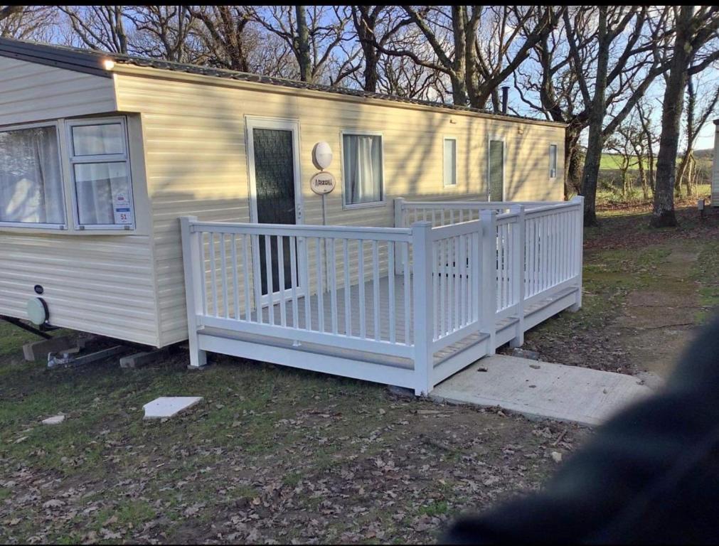 a mobile home with a white porch and fence at 51 oaklands in Cowes
