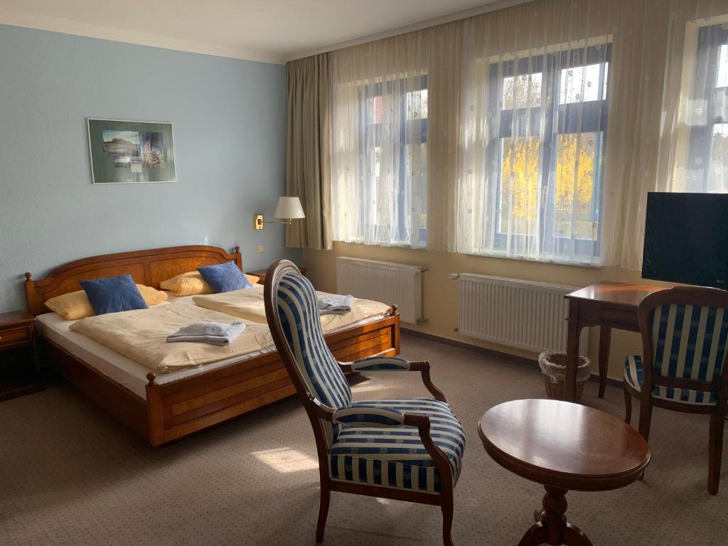 a bedroom with a bed and a chair and a table at Ryck-Hotel Garni in Greifswald