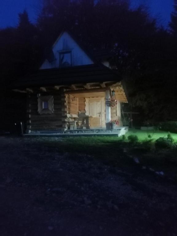 een klein huis 's nachts met groen licht bij Domek na Karolce in Ochotnica Górna