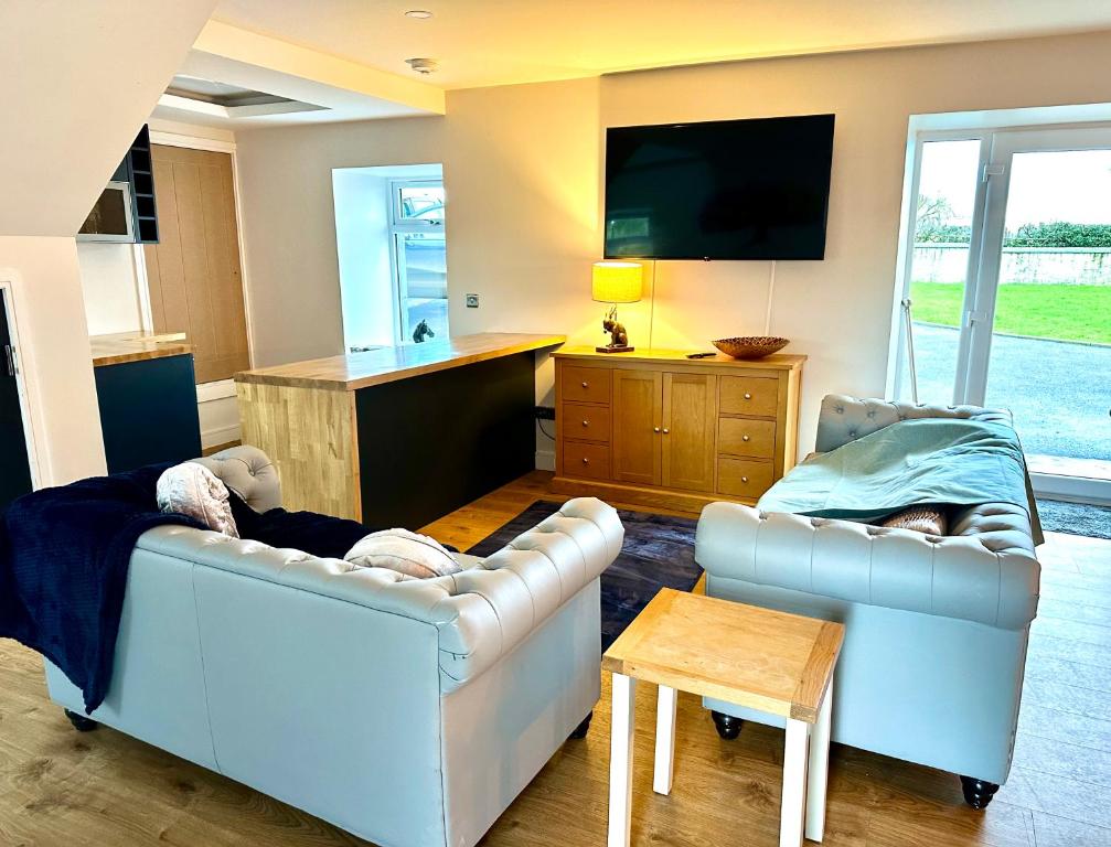 a living room with two couches and a flat screen tv at The Hideaway - Farm Stay with hottub, pool table and outdoor cinema in Newmilns