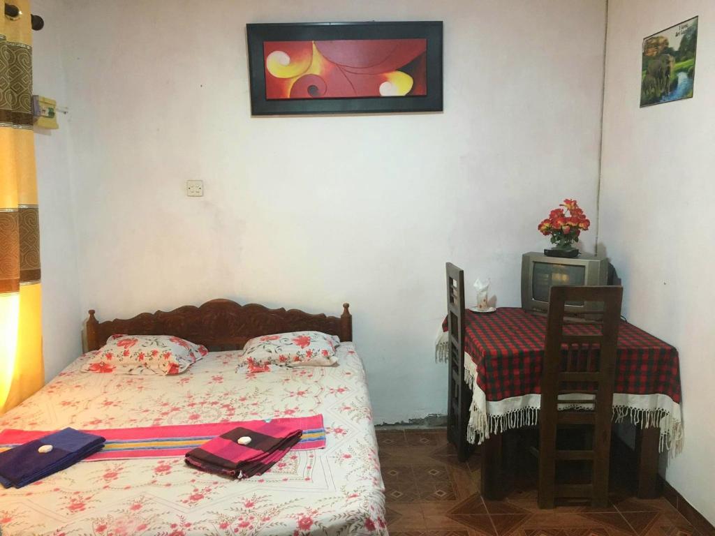 a small bedroom with a bed and a table at LD RoomA DunhidA in Badulla