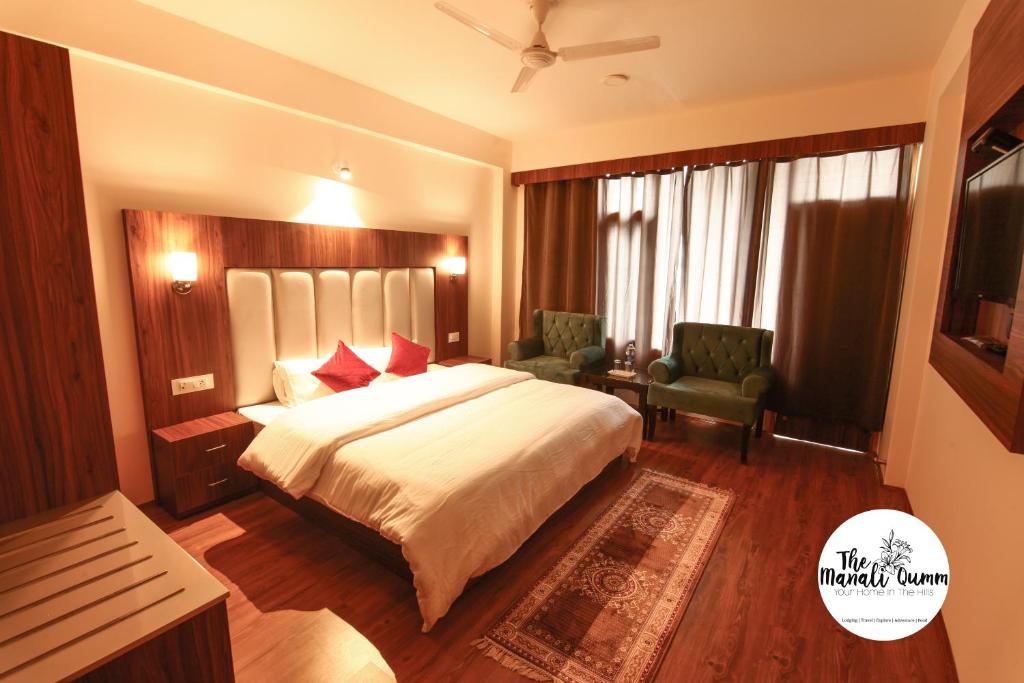 een hotelkamer met een groot bed en een stoel bij Manali Qumm in Manāli