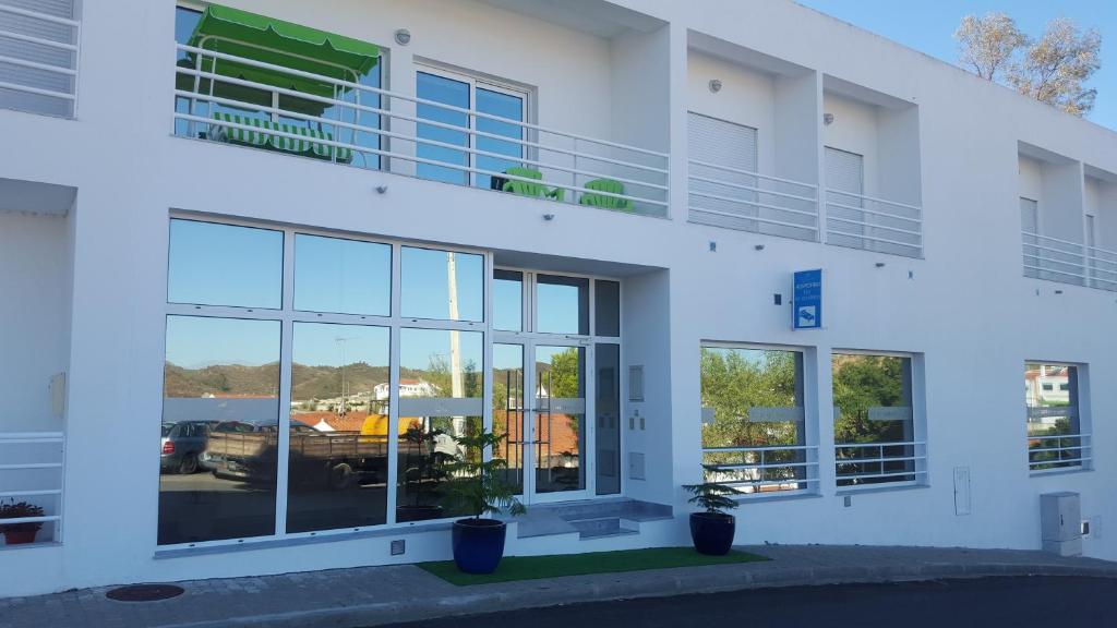 a white building with windows and potted plants at Hospedaria Flor do Guadiana in Mértola