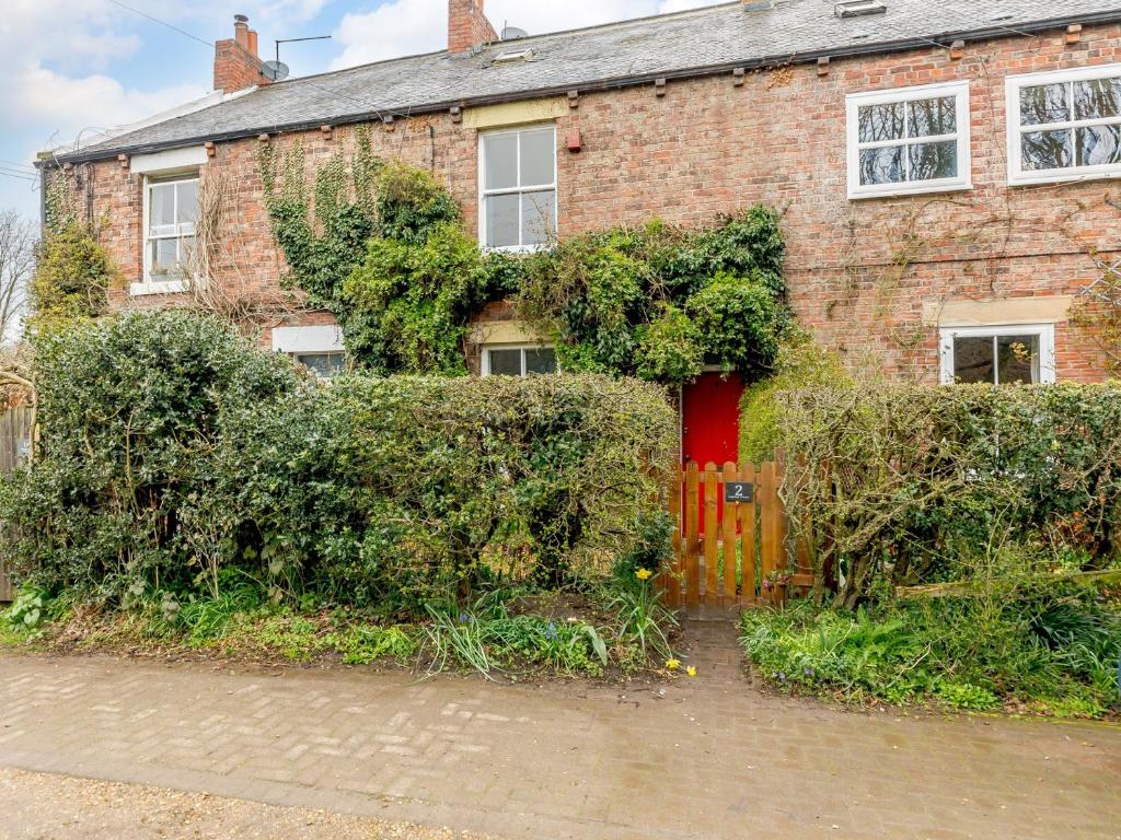 a brick house with a red door and bushes at 4 Bed in Wylam 90433 in Wylam