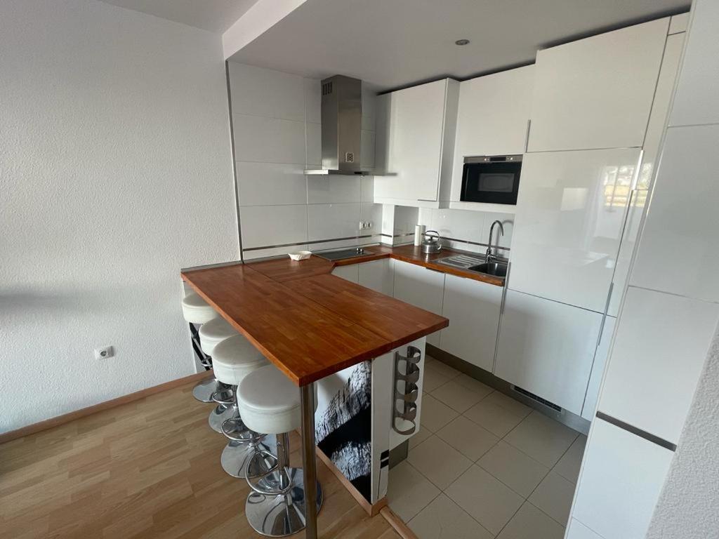 cocina con armarios blancos y encimera de madera en Apartamento turístico Cristóbal Colón, en Huelva
