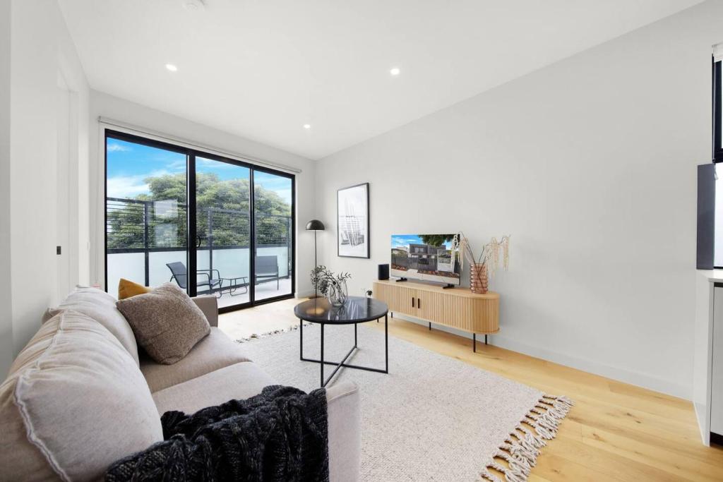 Sala de estar blanca con sofá y mesa en Parkside Chic Near Northland en Melbourne