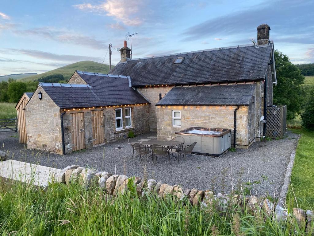 a stone house with a table and chairs in front of it at Netherraw in Newcastleton