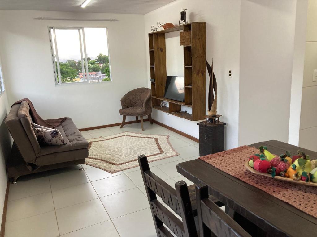 a living room with a table and a chair at Recanto das Pedras Floripa in Florianópolis