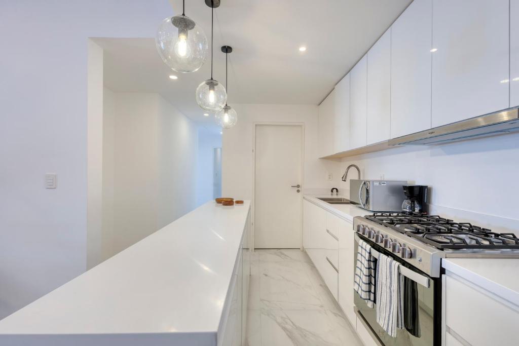 a kitchen with white cabinets and a stove top oven at Lumina at Marea Cabo San Lucas in Cabo San Lucas