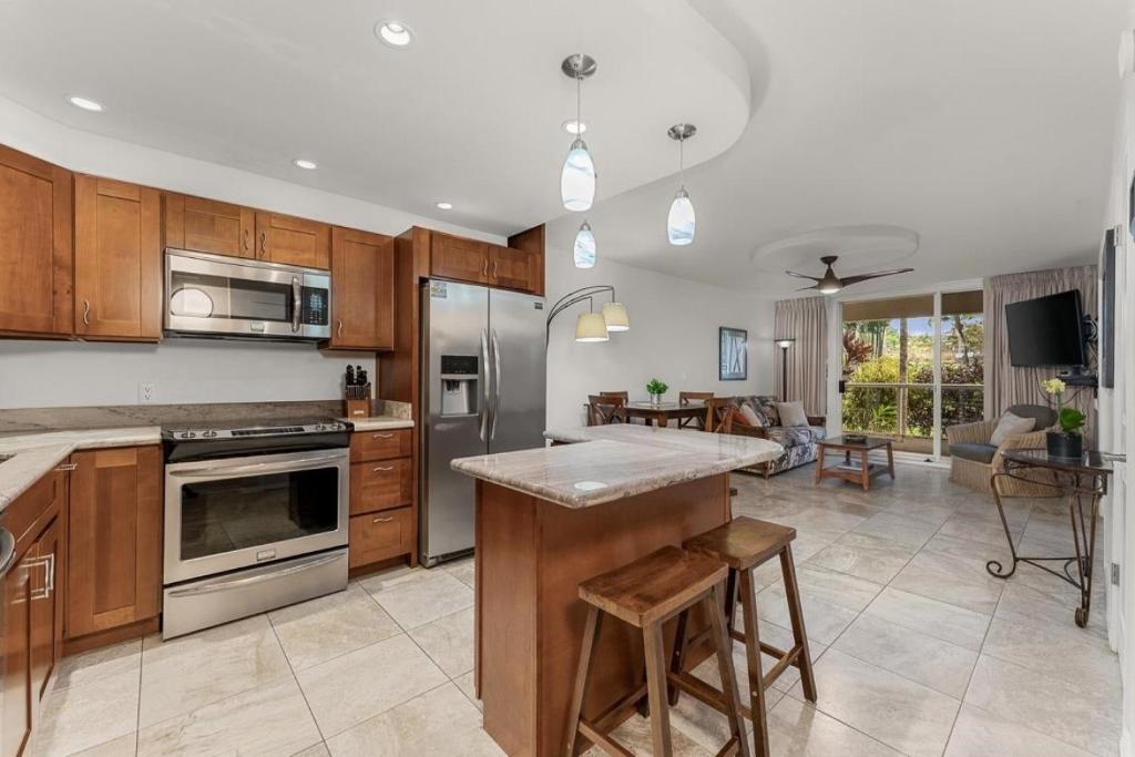 a kitchen with wooden cabinets and stainless steel appliances at NEW Luxury Condo at Kameole Beach in Wailea