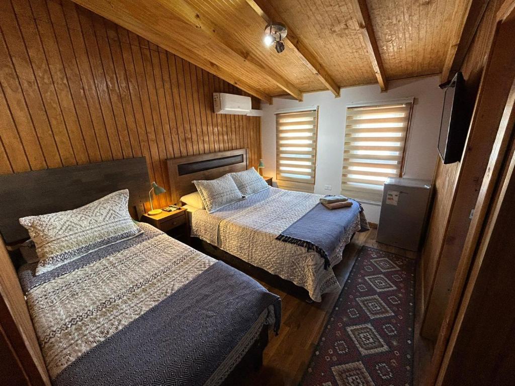 a bedroom with two beds and a television in it at Hostal Senderos del Sur in Freire