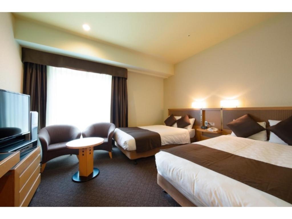 a hotel room with two beds and a flat screen tv at Hotel Nagoya Garden Palace - Vacation STAY 25771v in Nagoya