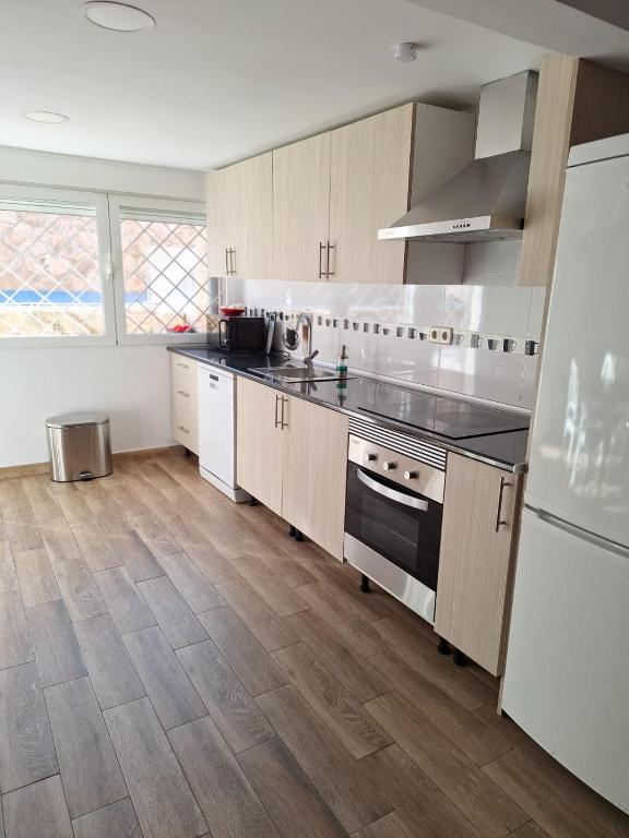 a kitchen with white appliances and wooden floors at Apartamento cercano a IFEMA, Aeropuerto, Clinica Universitaria Navarra y Civitas Metropolitano in Madrid