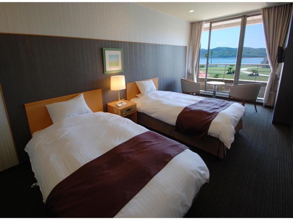 una camera d'albergo con due letti e una finestra di Hotel Alegria Gardens Amakusa - Vacation STAY 40454v ad Amakusa