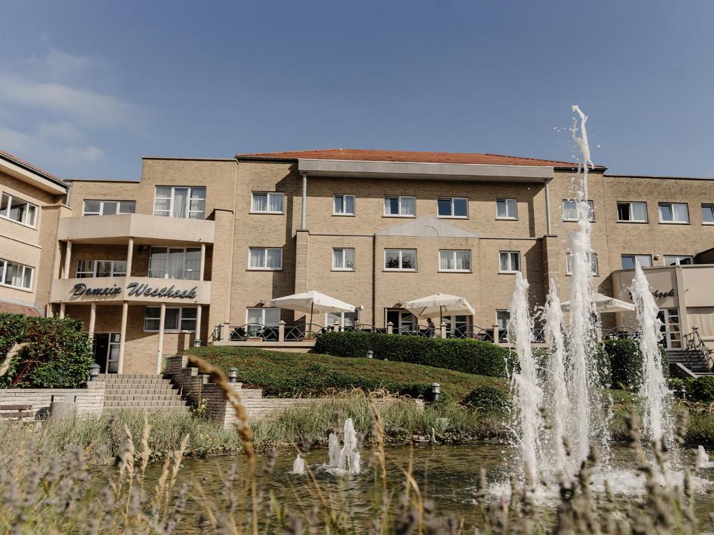 a hotel with a fountain in front of a building at Domein Westhoek in Oostduinkerke