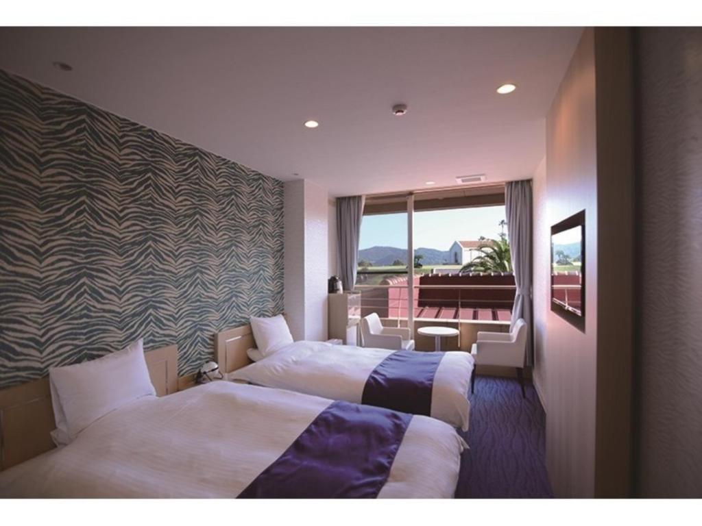 天草市にあるHotel Alegria Gardens Amakusa - Vacation STAY 40455vのベッド2台とバルコニーが備わるホテルルームです。