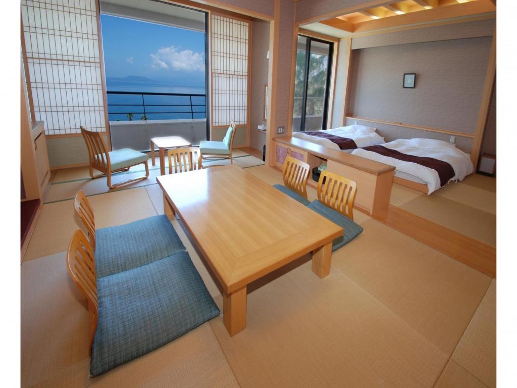 Schlafzimmer mit einem Bett, einem Tisch und Stühlen in der Unterkunft Hotel Alegria Gardens Amakusa - Vacation STAY 40451v in Amakusa