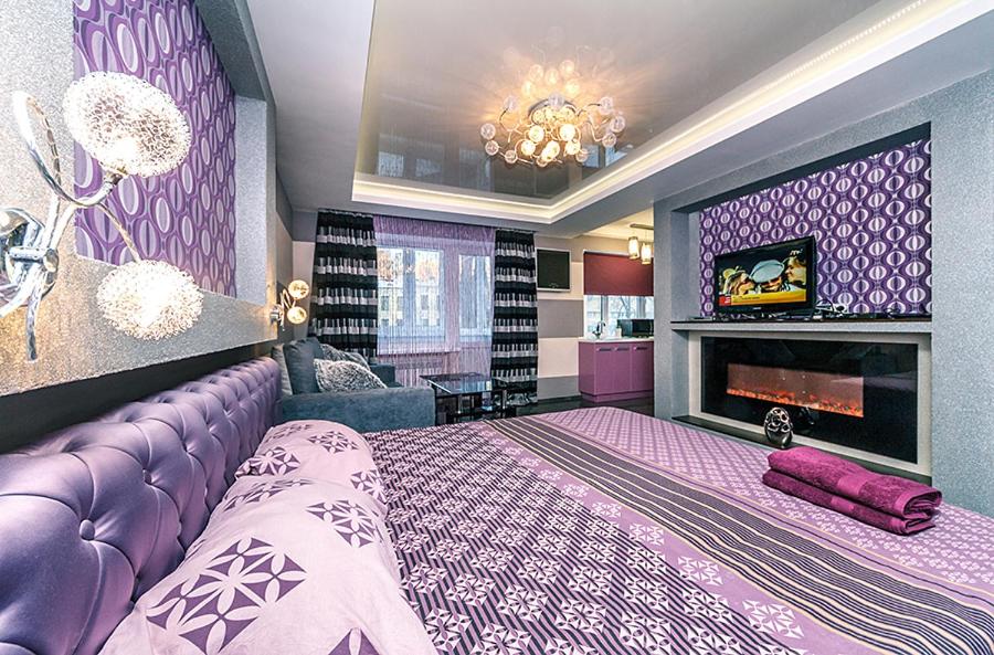 een paarse slaapkamer met een groot bed en een open haard bij Hotrent Bessarabka Arena in Kiev