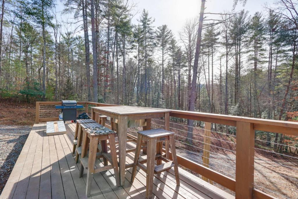 a wooden deck with a table and chairs and trees at Forested Ellijay Cabin Rental with Private Hot Tub! in Ellijay