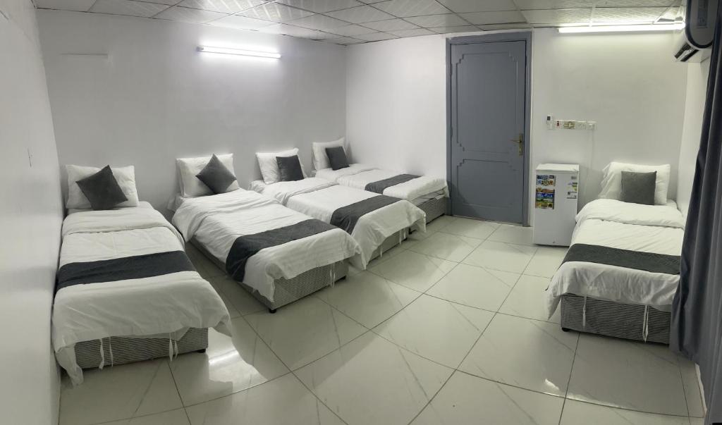 3 camas en una habitación con paredes blancas en Safwat Alshindi Hotel, en Medina