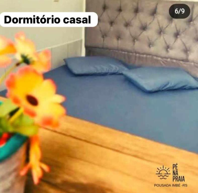um quarto com uma cama com lençóis azuis e almofadas azuis em Pousada Pé na Praia em Imbé