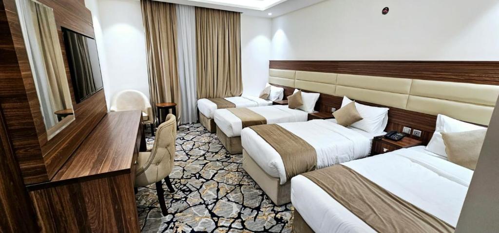 EWG Al Mashaer Hotel في مكة المكرمة: غرفة فندقية بسريرين ومكتب