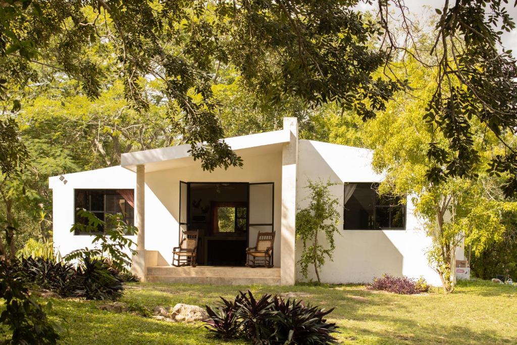 uma casa branca com duas cadeiras num quintal em Casa Rancho- Finca única en Yucatán em Hoctún