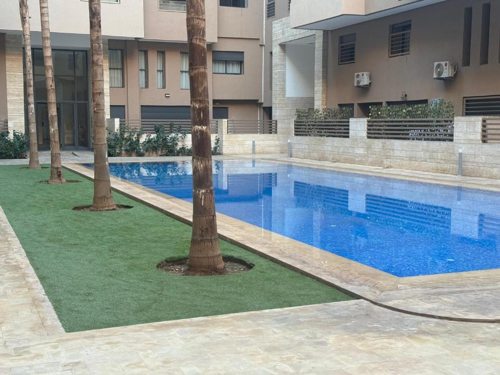 una piscina con 2 palmeras frente a un edificio en Appart Kech Menera en Marrakech