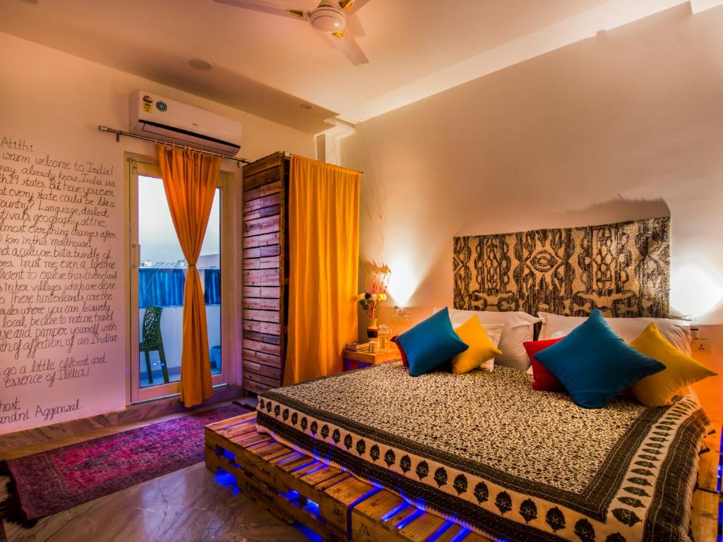 a bedroom with a bed with colorful pillows and a window at Gypsy Nest Hostel in Agra