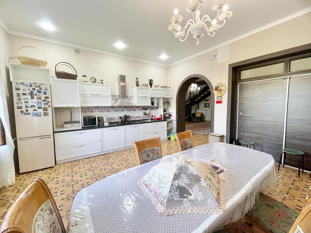 Spacious and cozy villa في بيشكيك: مطبخ مع طاولة وكراسي وغرفة طعام