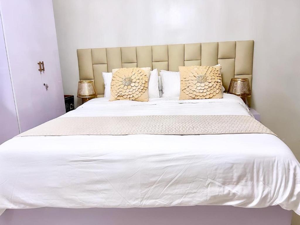 een slaapkamer met een groot bed met witte lakens en kussens bij Condo Home in Puerto Princesa near PPS Airport in Puerto Princesa City