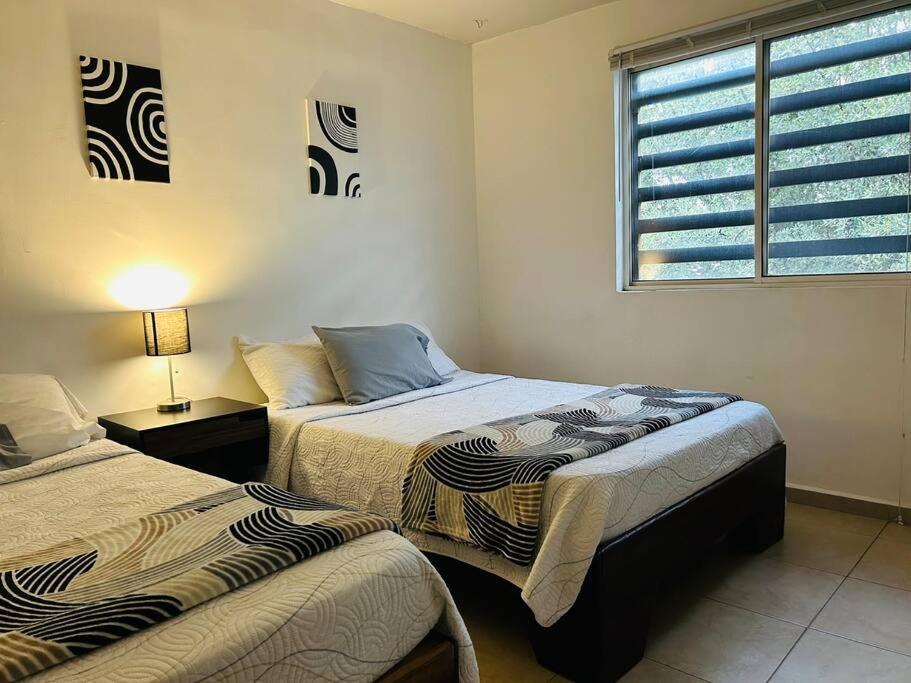 2 camas en una habitación con ventana y 1 cama sidx sidx sidx sidx en Great house in Monterrey 3 bedroom wifi AC parking, en Monterrey